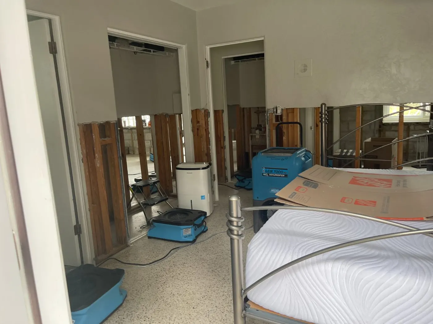 Commercial air movers and dehumidifier drying a bedroom after water damage